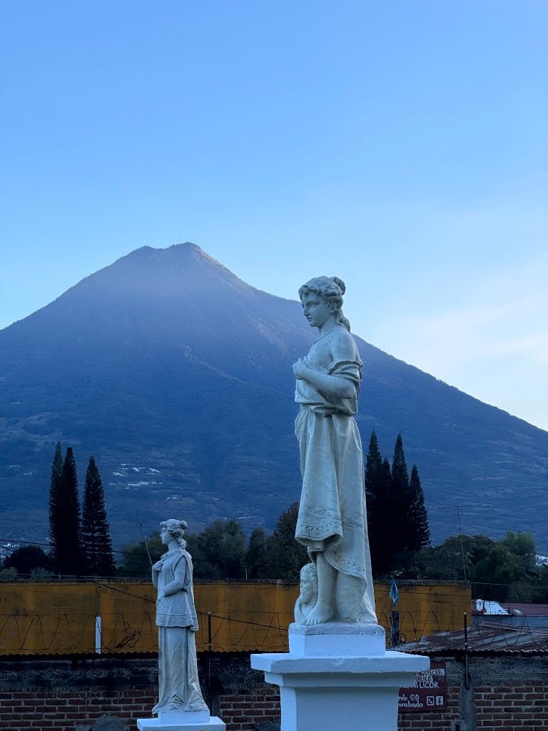 Classical statues with a volcano in the background