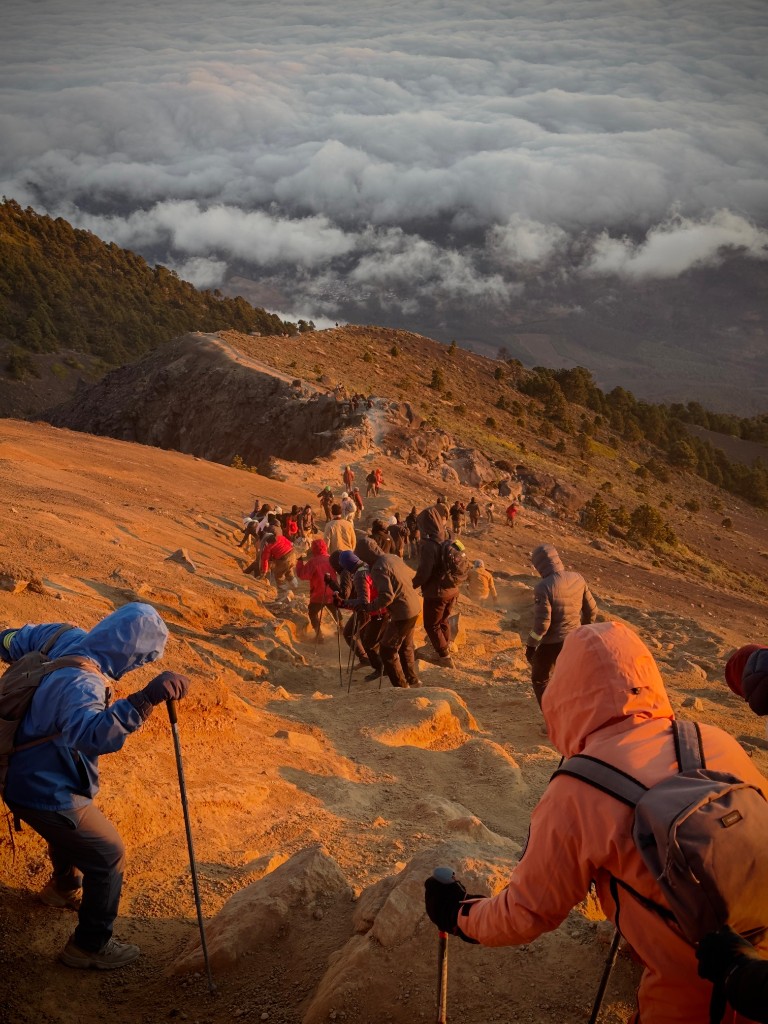 Hikers ascending a ridge above the clouds