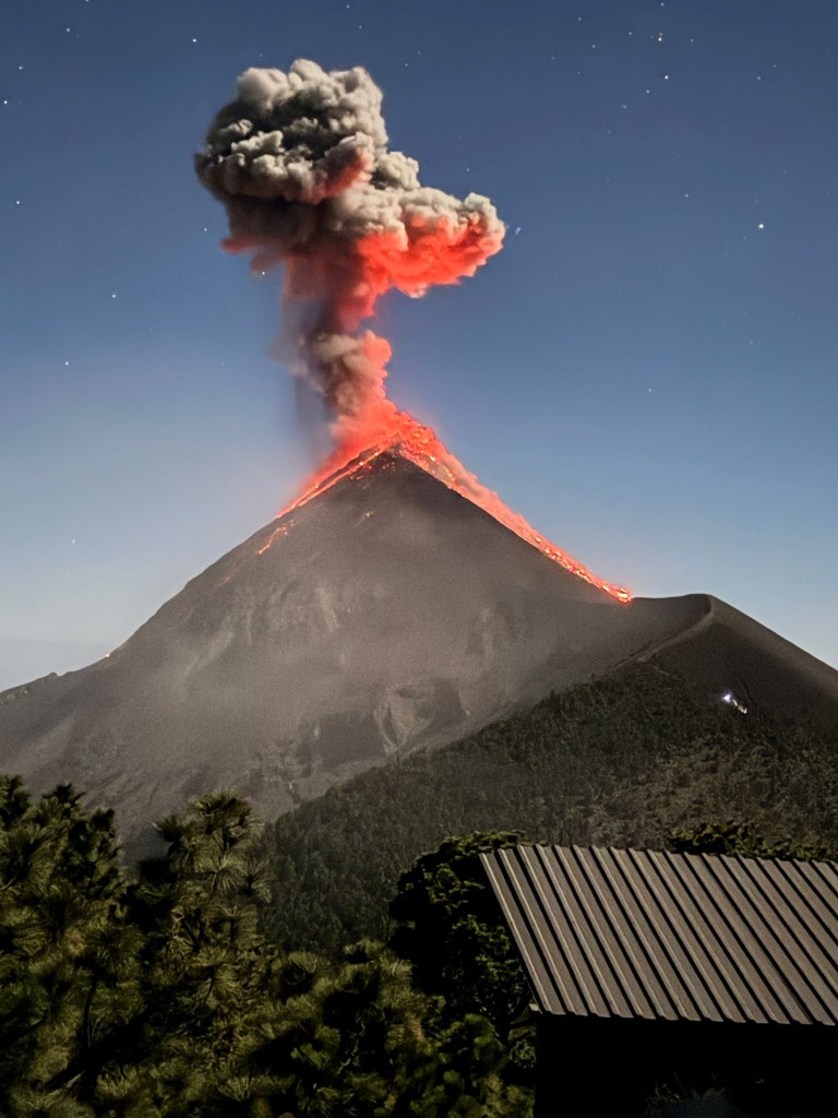 Volcano erupting at night under a starry sky